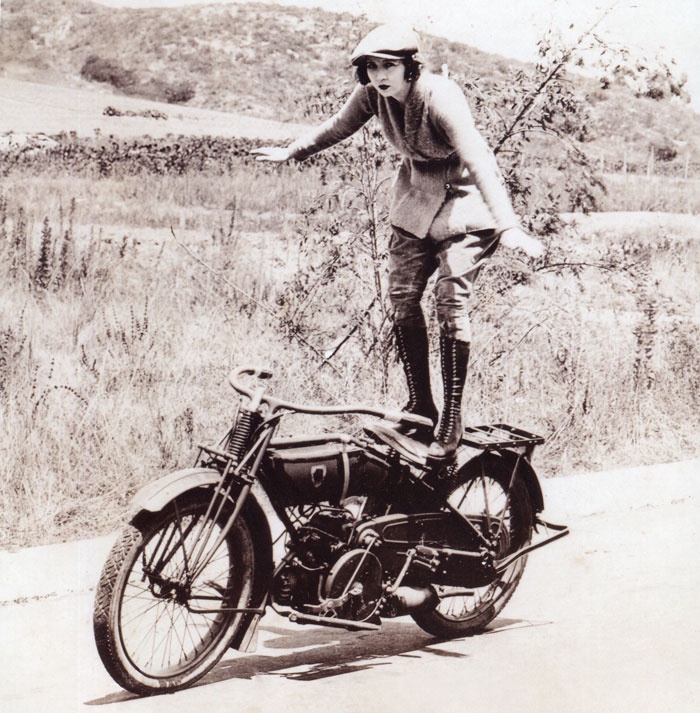 a woman riding a bike down a dirt road